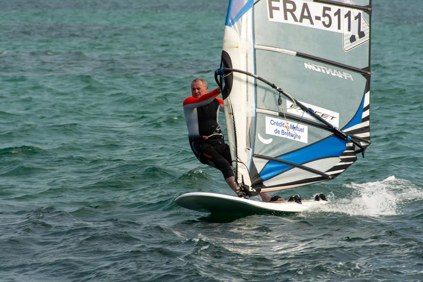 Dynamic windsurfer gliding across the sea, showcasing skill and thrill of water sports.