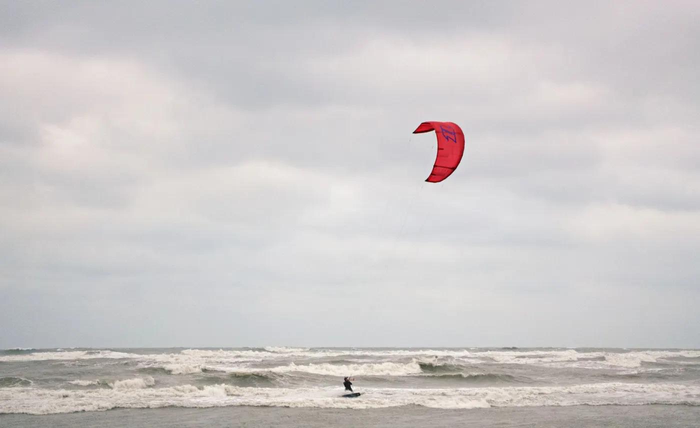 A kitesurfer enjoying the waves under a cloudy sky in Taoyuan, Taiwan.